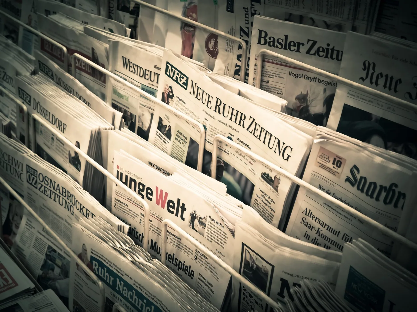 Wire rack displaying a row of folded German-language newspapers