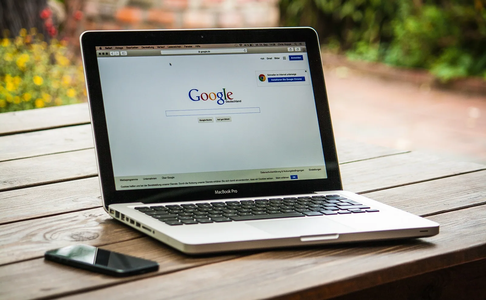 MacBook Pro on a wooden table displaying the Google search homepage