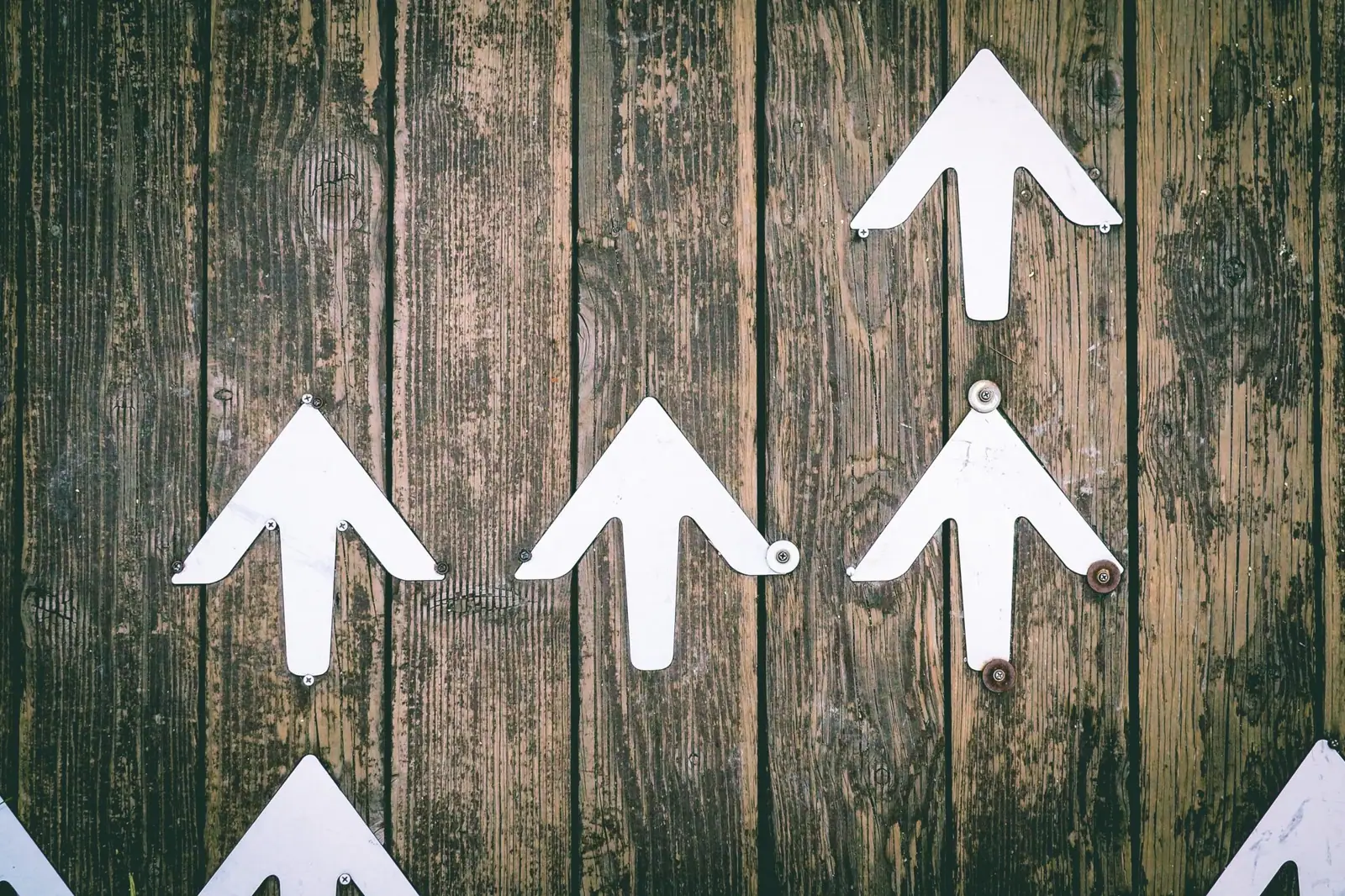 White upward-pointing arrows mounted on a weathered wooden plank wall