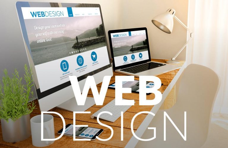 Desktop monitor and laptop on a desk displaying a web design template with WEB DESIGN text overlay