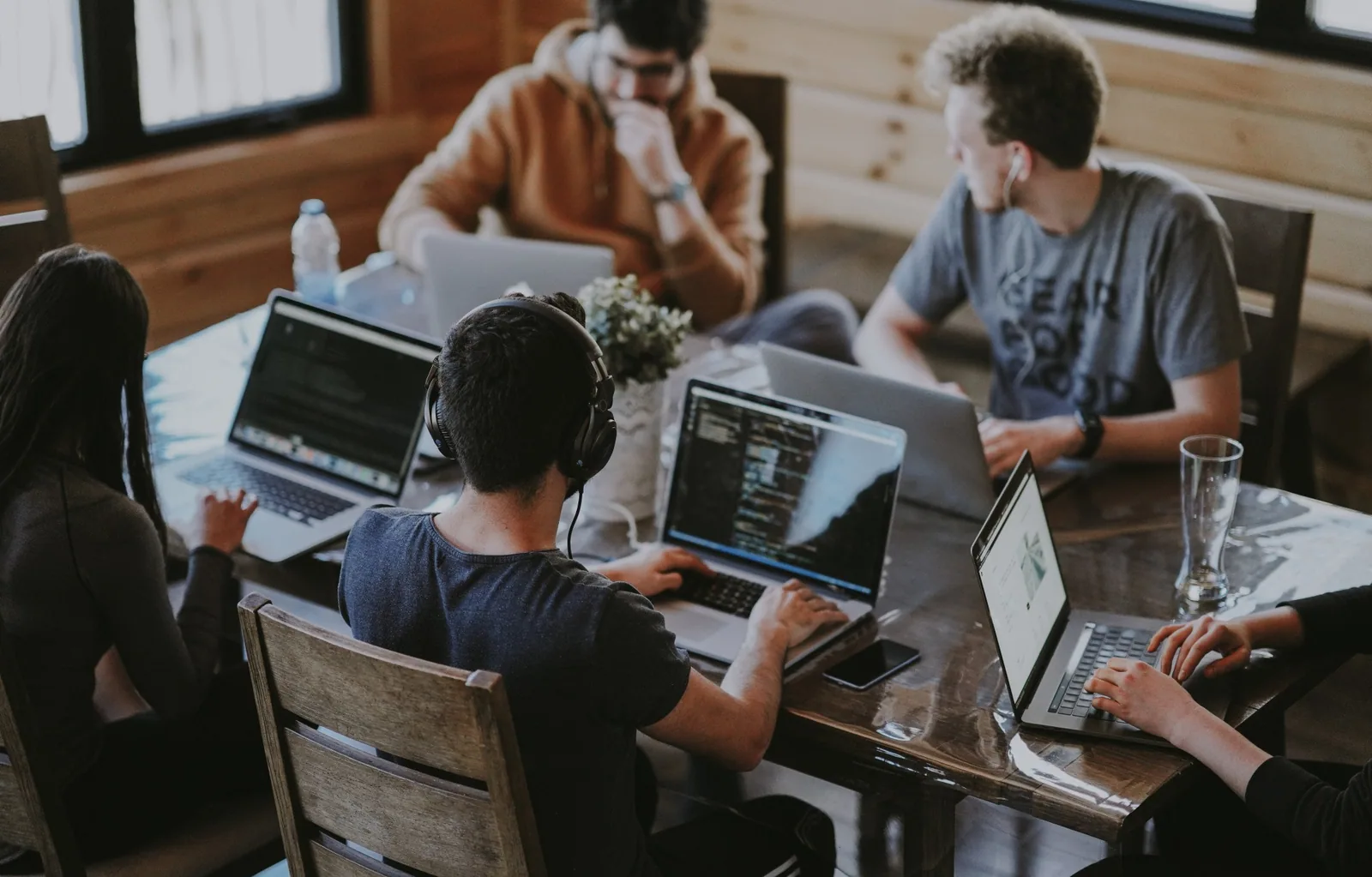 Group of young people working together on laptops at a wooden table