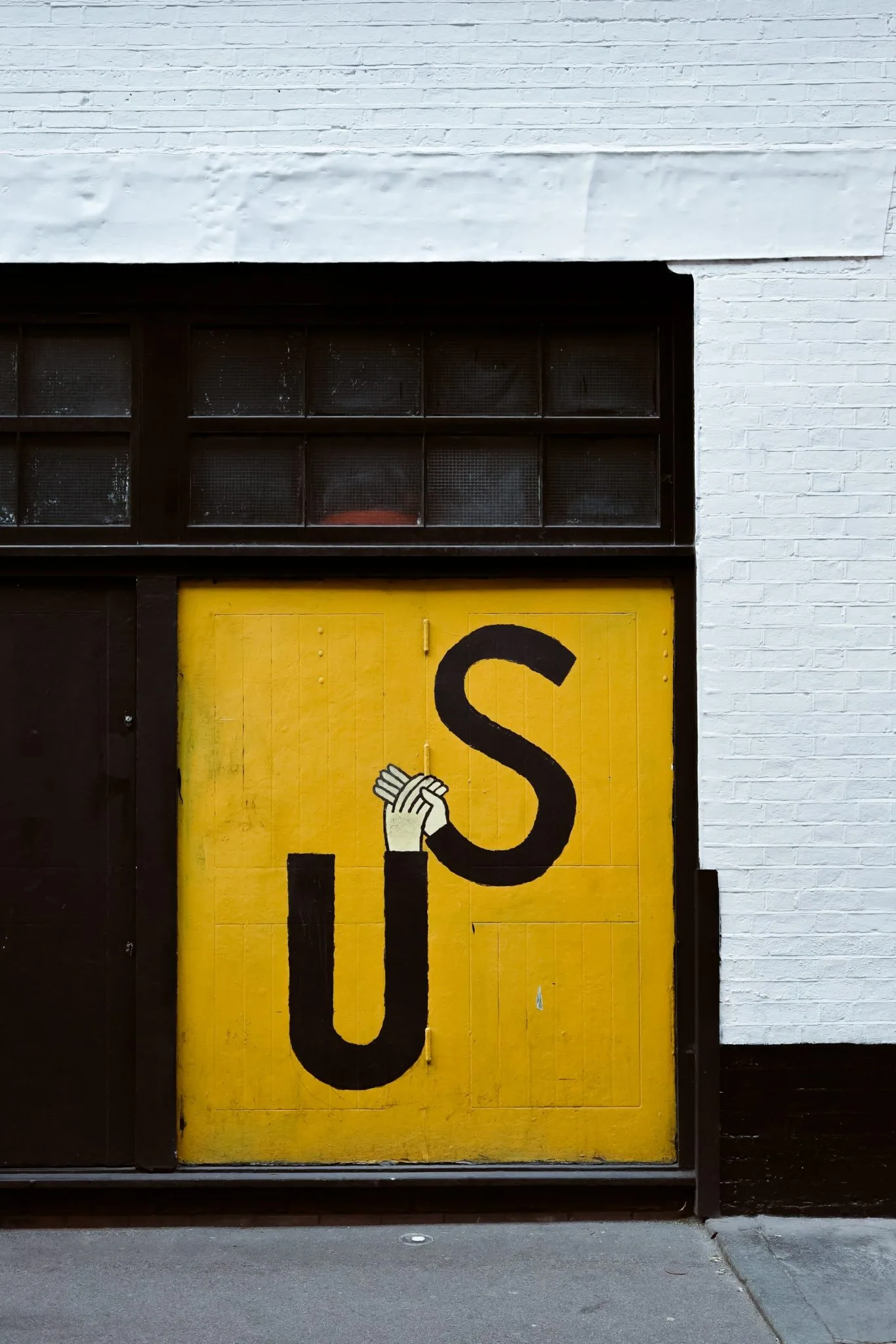 Yellow garage door painted with large U and S letters and clasped hands