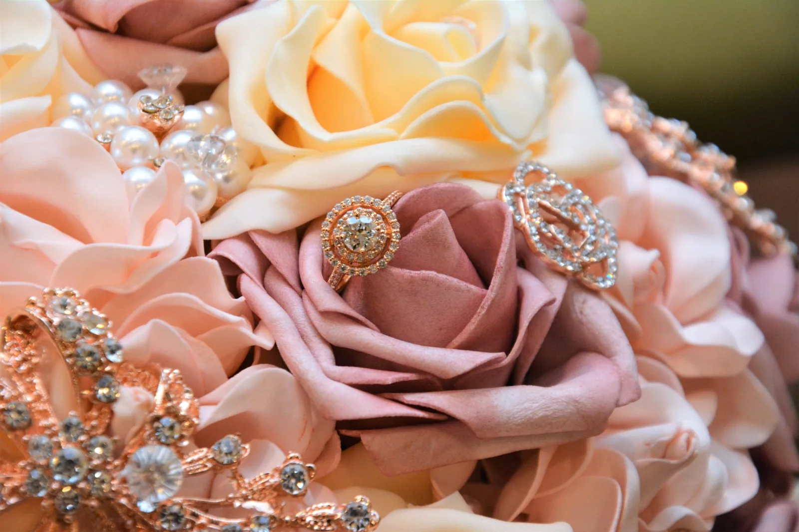 Bouquet of pink and cream roses accented with rhinestone brooches and pearls.
