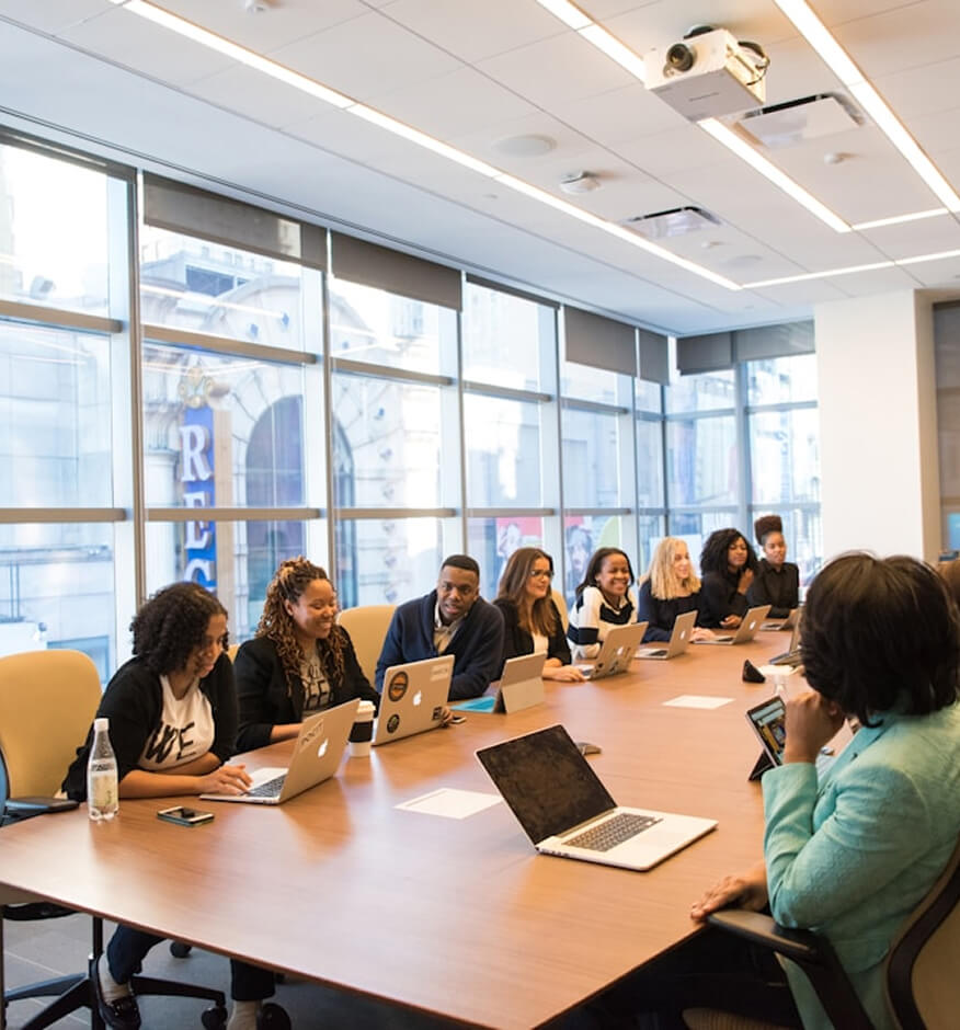 Diverse team meeting around a conference room table with laptops